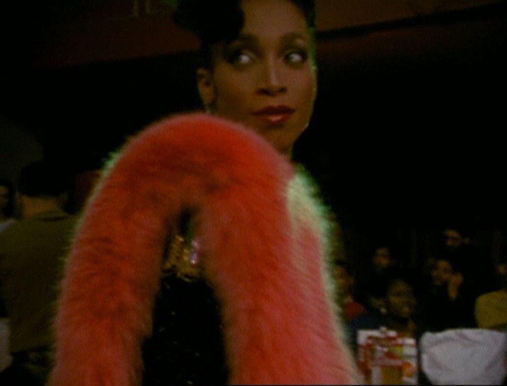 Another Black drag performer with a fur stole, looking over her shoulder.