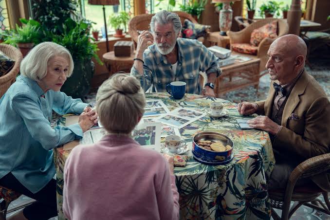 Elizabeth (Helen Mirren), Ron (Pierce Brosnan), Ibrahim (Ben Kingsley) and Joyce (Celia Imrie) sitting around a table with photos, tea and biscuits, obviously discussing something serious.